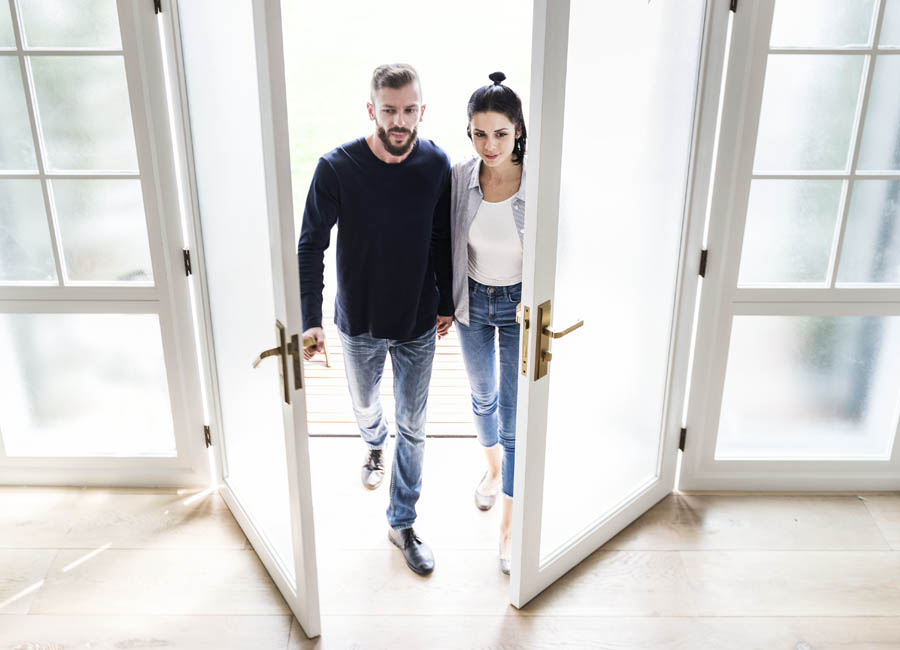 Pareja entrando en su casa nueva comprada gracias a okados